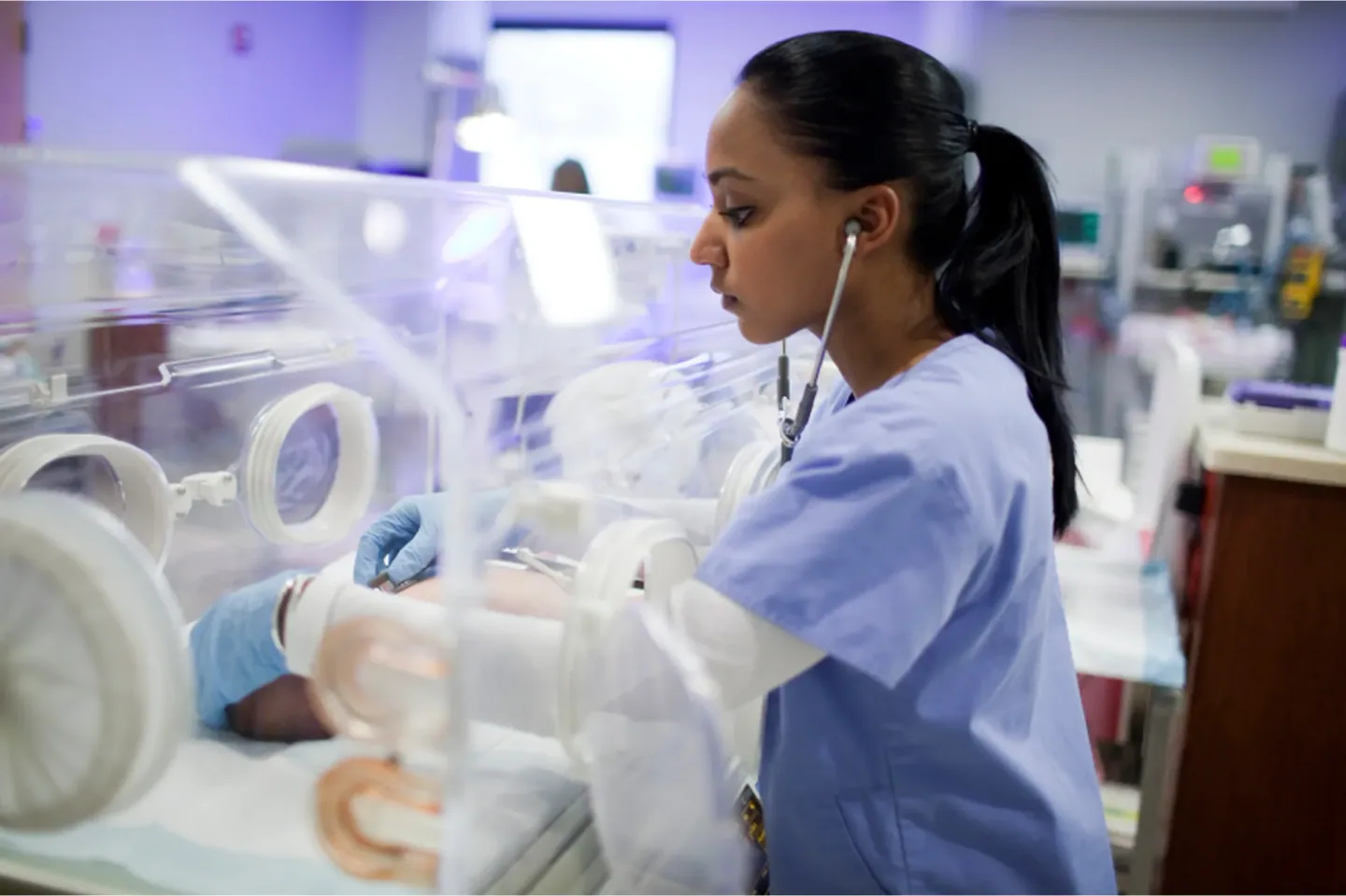 Neonatal care team member supporting a baby in the NICU